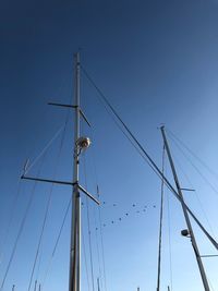 Low angle view of sailboat masts against clear blue sky