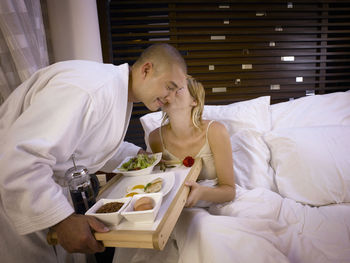 Young man eating food on bed