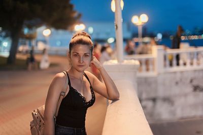 Portrait of woman standing in city at night