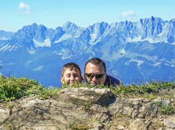 Portrait of man relaxing on mountain against sky