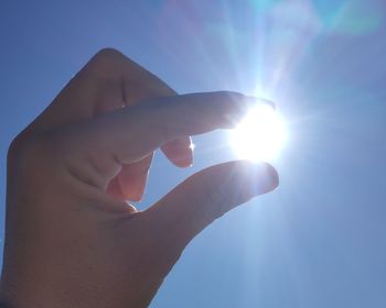 Midsection of person holding sun against sky