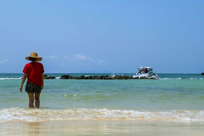 Rear view of person on beach against sky