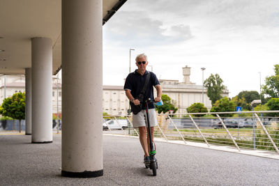 Commuter hipster man is using electric scooter on the outskirts of a city. eco transport concept