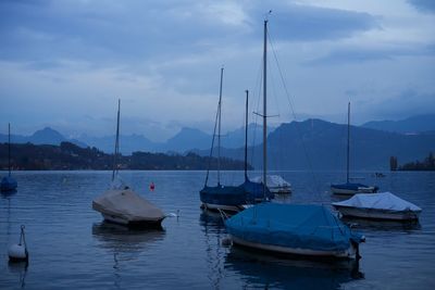 Sailboats moored in lake against sky