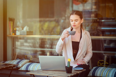 Young woman using mobile phone at table