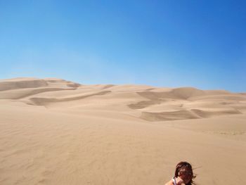 Woman on desert against clear blue sky