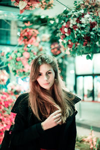 Portrait of young woman standing against tree
