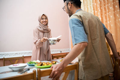 Excited woman holding food while looking at man