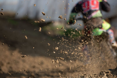 Unrecognized athlete riding a sports motorbike and muddy wheel on a motocross racing event