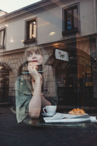 Reflection of woman in glass window on table