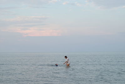 Men in sea against sky