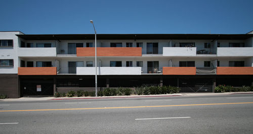 Road by residential buildings against clear sky