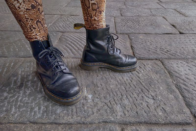 Low section of person standing on cobblestone with black boots