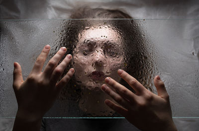 Close-up of woman seen through wet glass