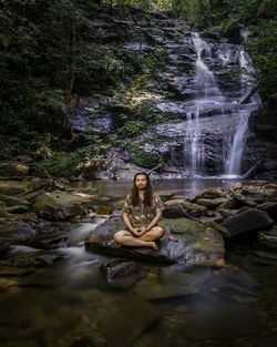 Man sitting on rock in forest