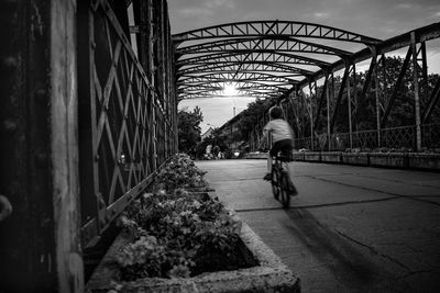 Man riding bicycle on bridge in city