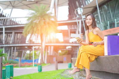 Young woman smiling while sitting on mobile phone