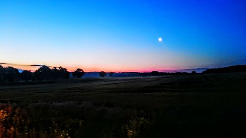 Scenic view of silhouette field against clear sky at sunset