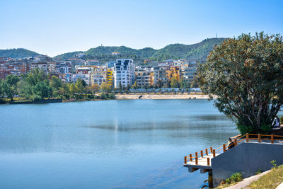 Scenic view of river by buildings against clear sky