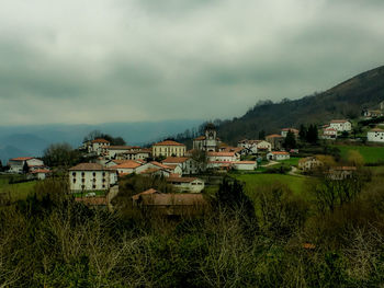 Houses on green landscape against sky