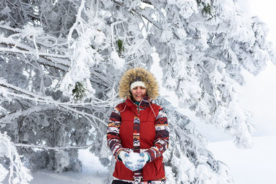 Portrait of smiling young woman standing on snow