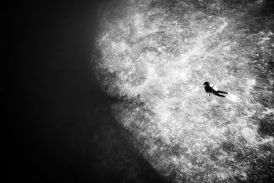 Silhouette person swimming in sea at night