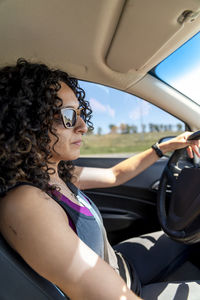 Young serious woman driving a car on the road.