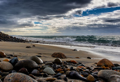 Scenic view of beach against cloudy sky