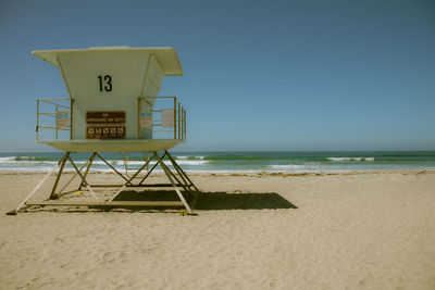 Lifeguard hut at beach against clear blue sky