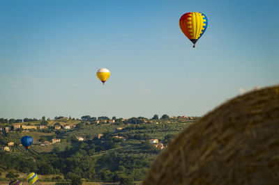 Hot air balloons flying over landscape against sky