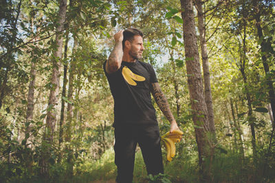 Man standing holding bananas while standing in forest