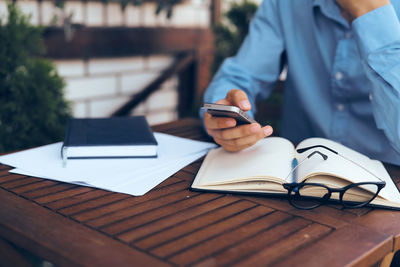 Man using mobile phone while sitting on table