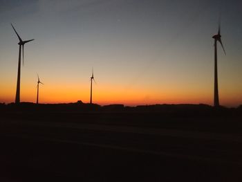 Silhouette windmill on field against sky during sunset