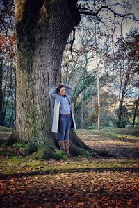 Full length of woman standing against trees in forest