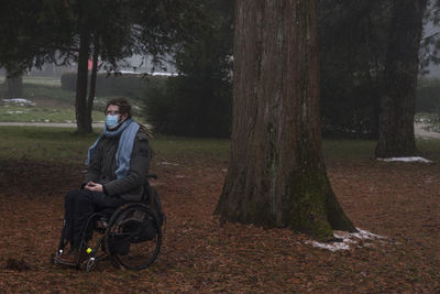 Man sitting on wheelchair in park during winter