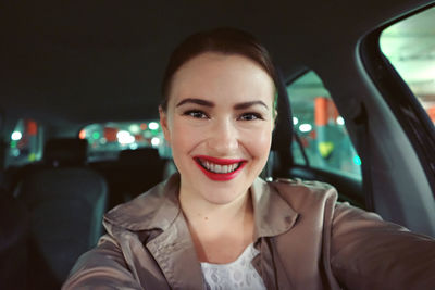 Portrait of cheerful young woman in car