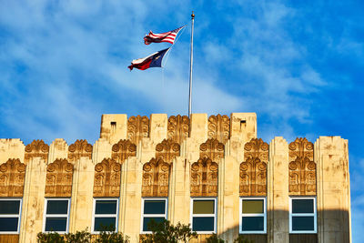 Low angle view of usa and texas flag against sky