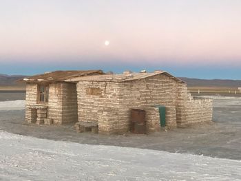 Historic building by mountain against sky during winter