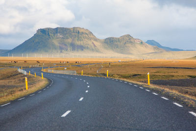 Road by mountains against sky