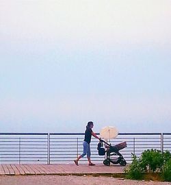 Woman standing by sea against clear sky