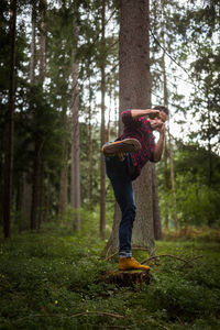 Full length of senior man on tree trunk in forest