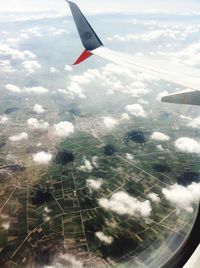 Aerial view of airplane wing over clouds