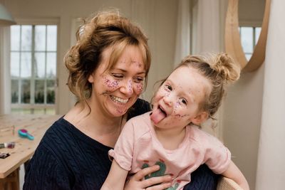 Mother and daughter having fun playing dress up at home