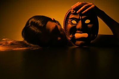 Close-up of woman holding mask on table