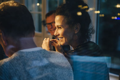 Smiling senior woman looking at man during dinner party