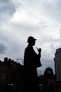 Silhouette man standing against buildings in city against sky