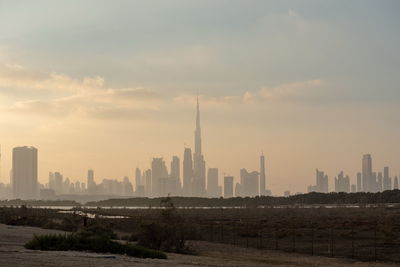 Modern buildings in city against sky during sunset