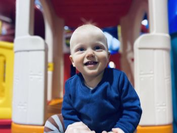Portrait of happy cute baby boy sitting on outdoor play equipment