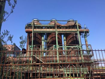 Low angle view of abandoned factory against clear blue sky