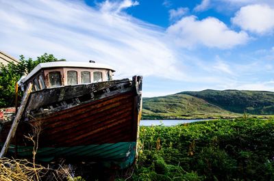 Boat moored by trees against sky